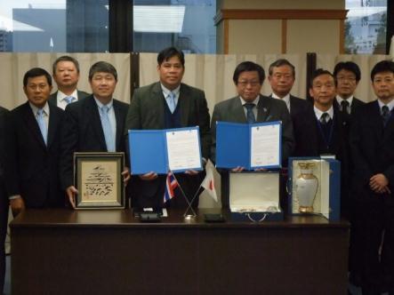 額や色紙に飾られた書類をカメラに向けている男性たちの写真