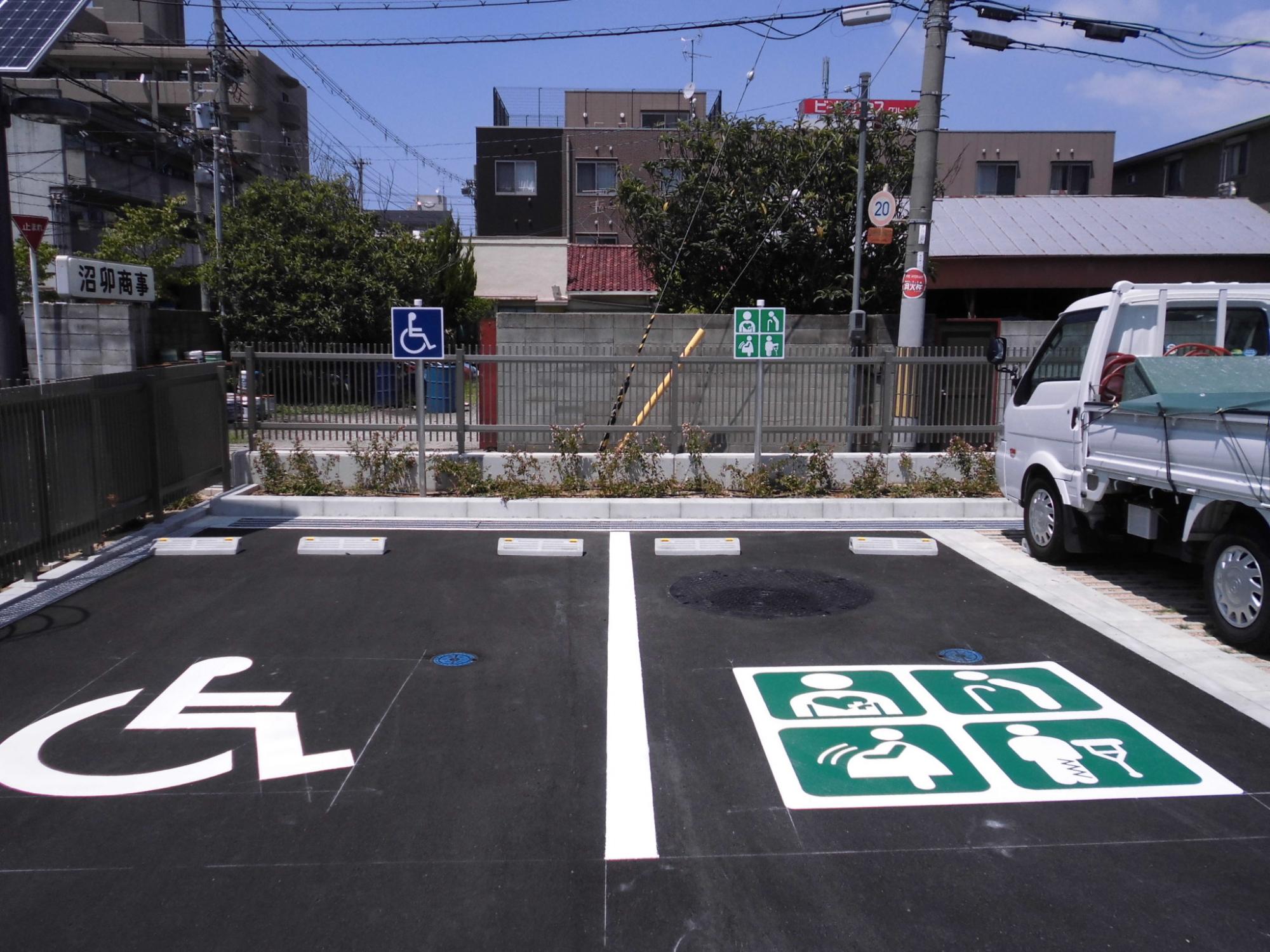 譲り合いスペース及び身障者用駐車スペースのマークがある舗装された駐車場を写した写真