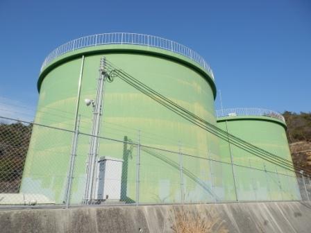 二つ並び無機質で緑色の大きな筒形の高区配水池の写真
