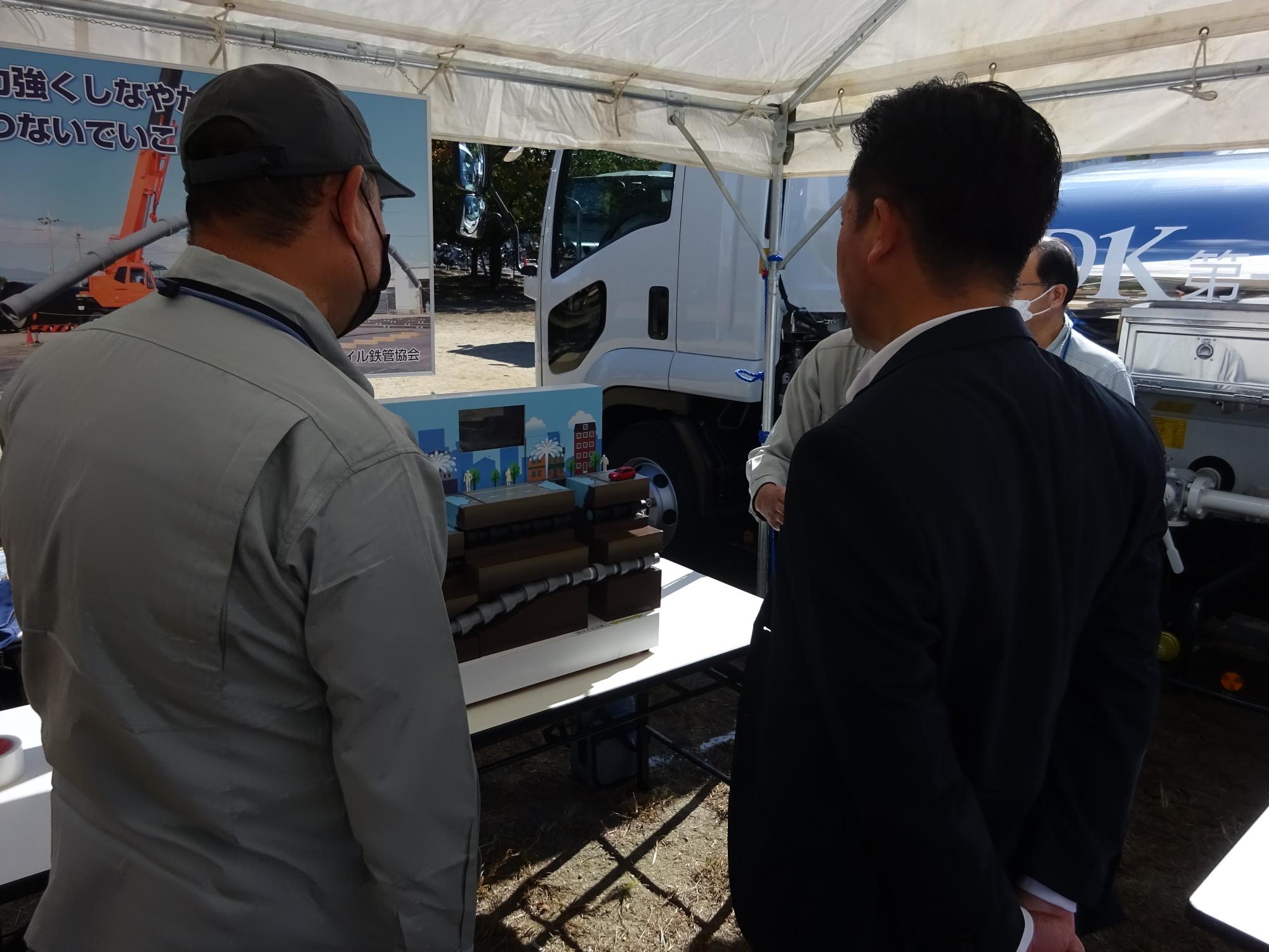 水道管の模型展示の説明をうける大阪狭山市長