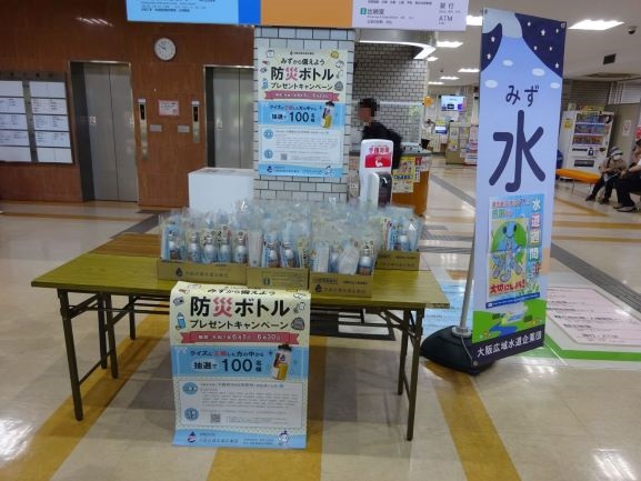 机の上に置かれた配布用備蓄水とバナースタンド等