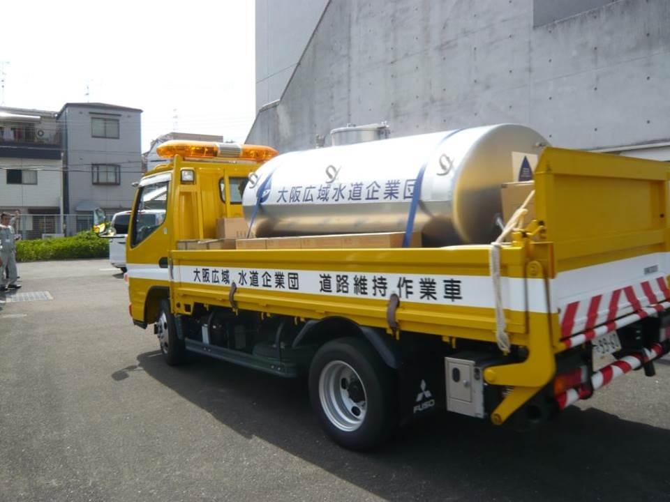 大阪広域水道企業団と書かれたタンクを積んだ、黄色い給水車の写真