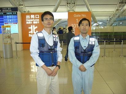 関西国際空港の出発ロビーで、作業服姿の二人の職員が並んでいる写真