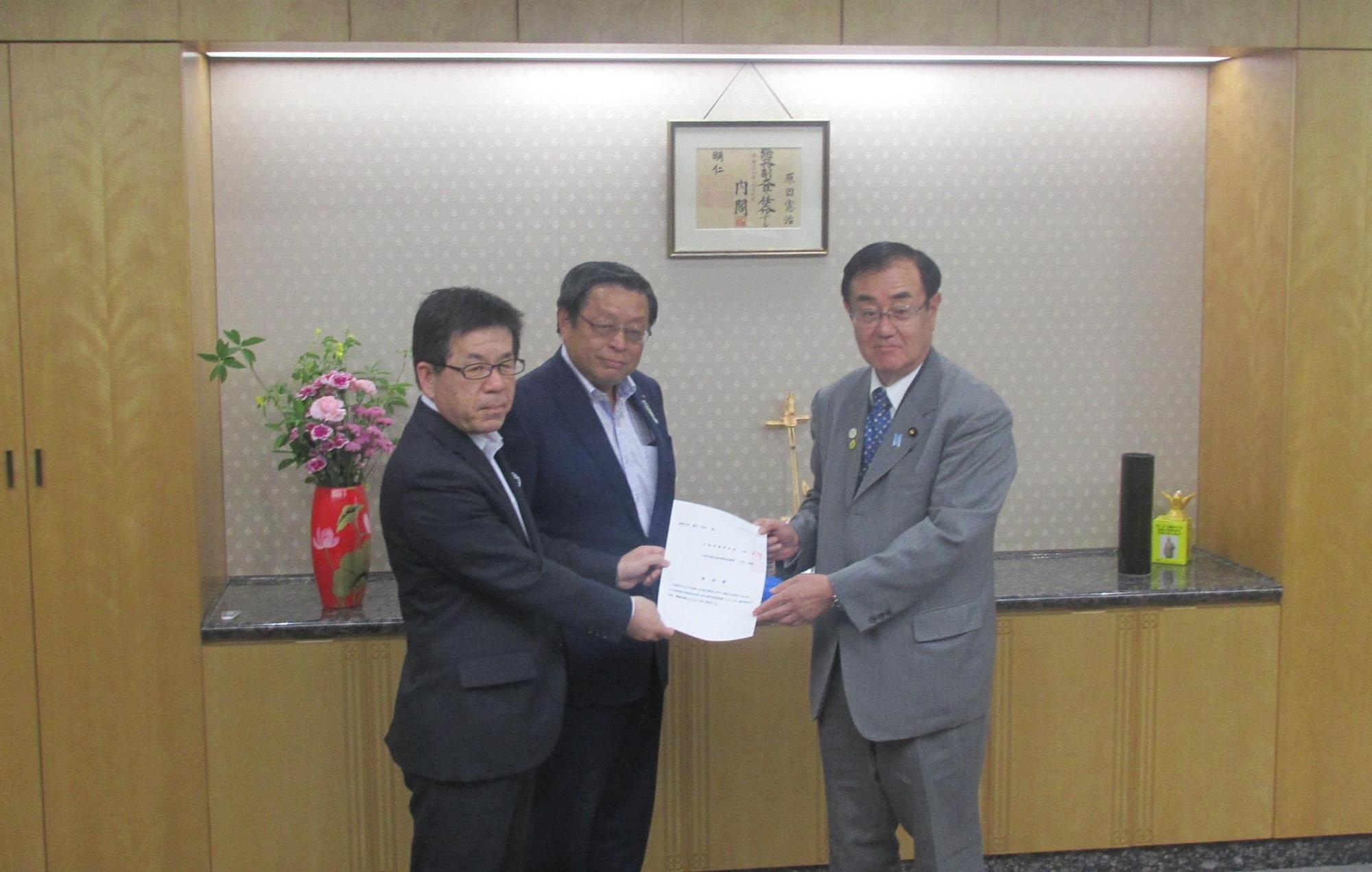 スーツを着た上森能勢町長と竹山企業長が、原田総務副大臣に要望書を手渡している写真